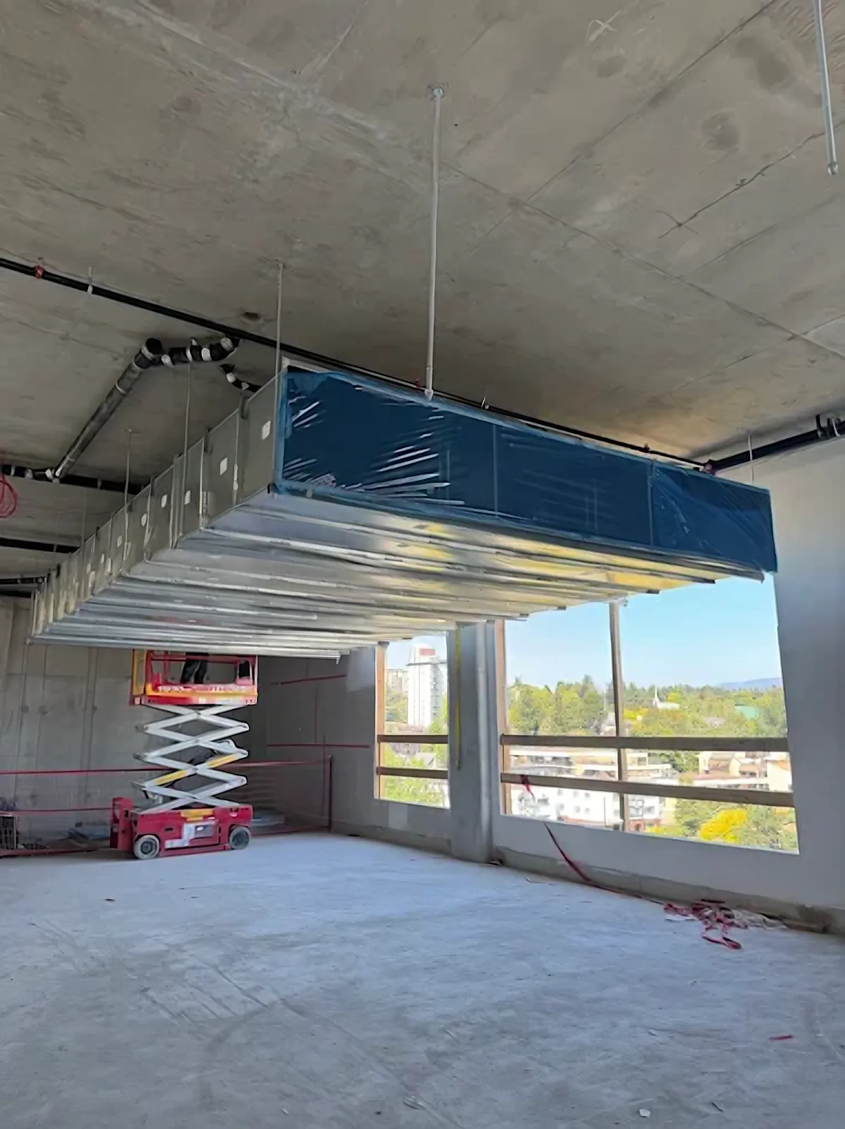 Commercial mechanical room exhaust ductwork hung from a concrete slab