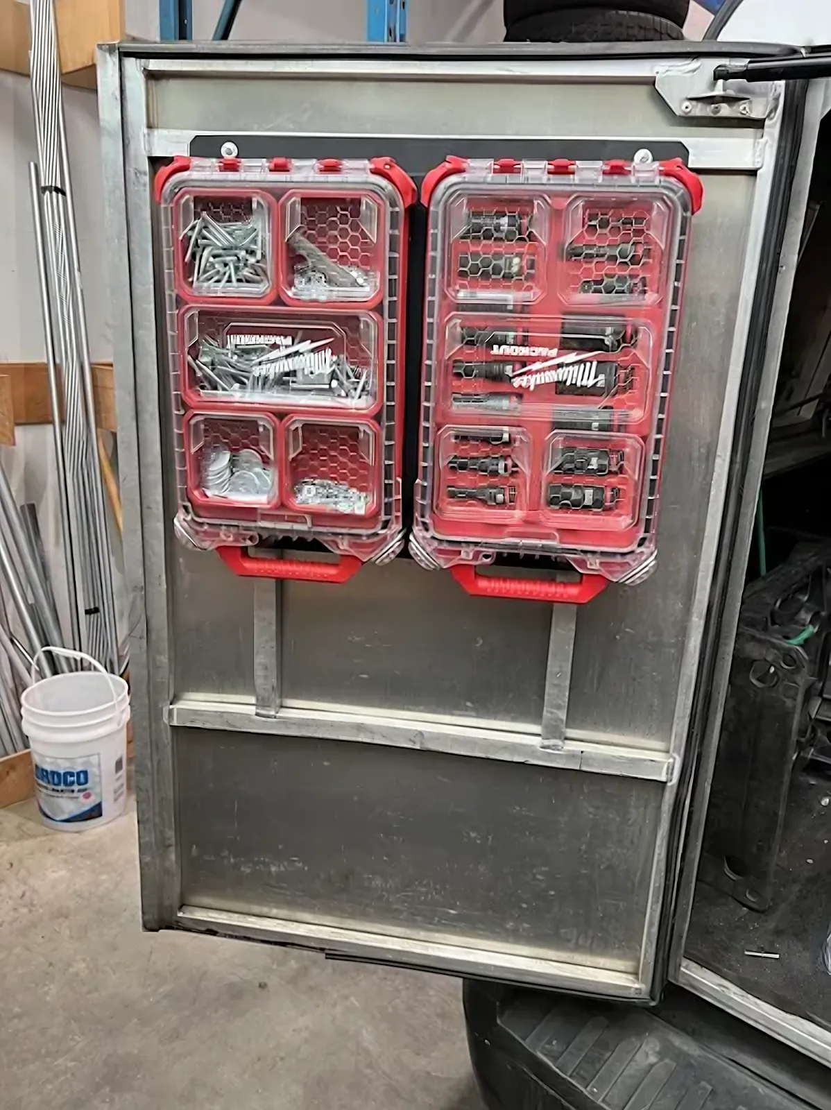 Custom sheet metal racks holding Milwaukee Packout organizers on a contractor van door
